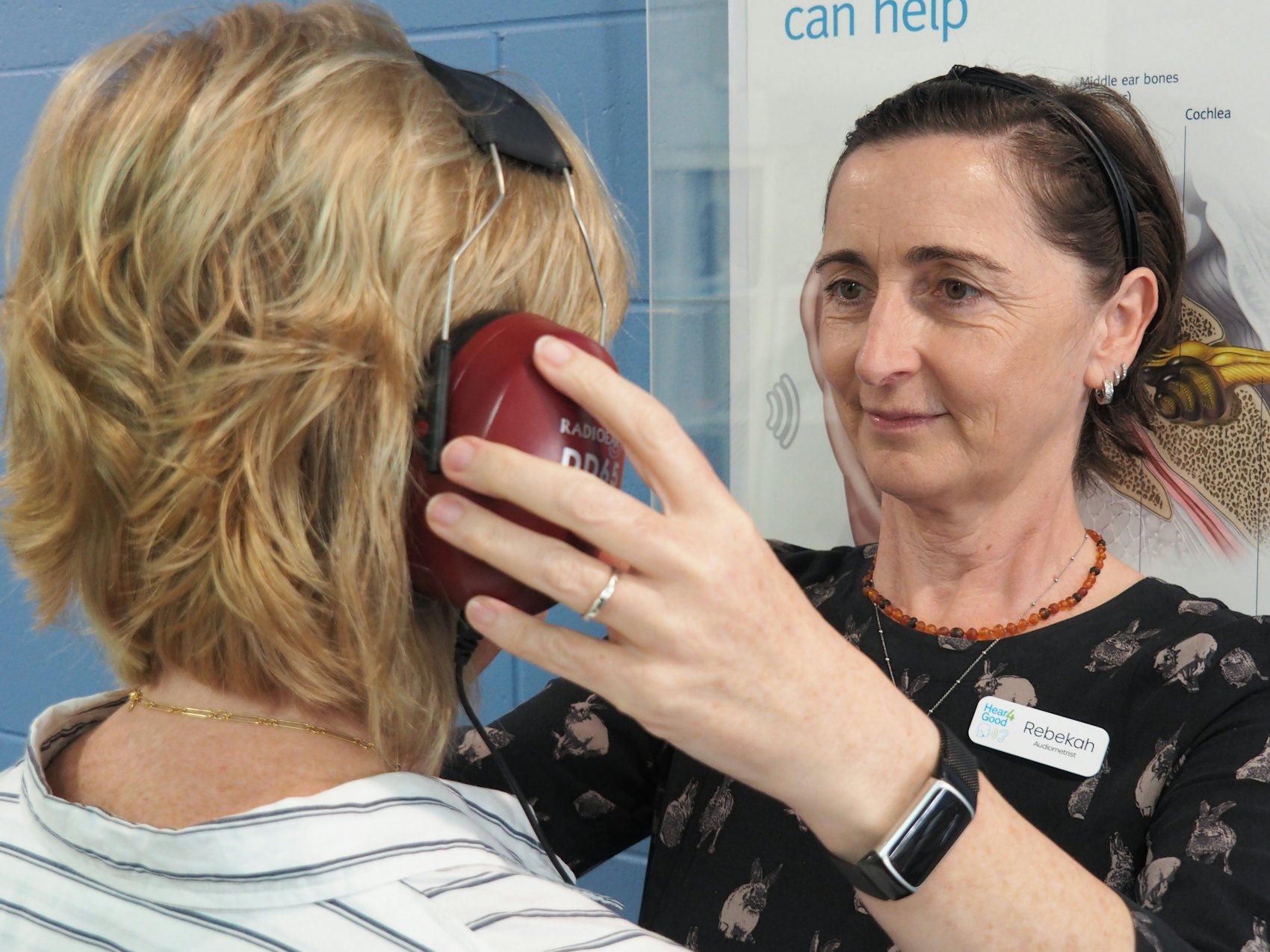 An audiologist performing a hearing test on a woman