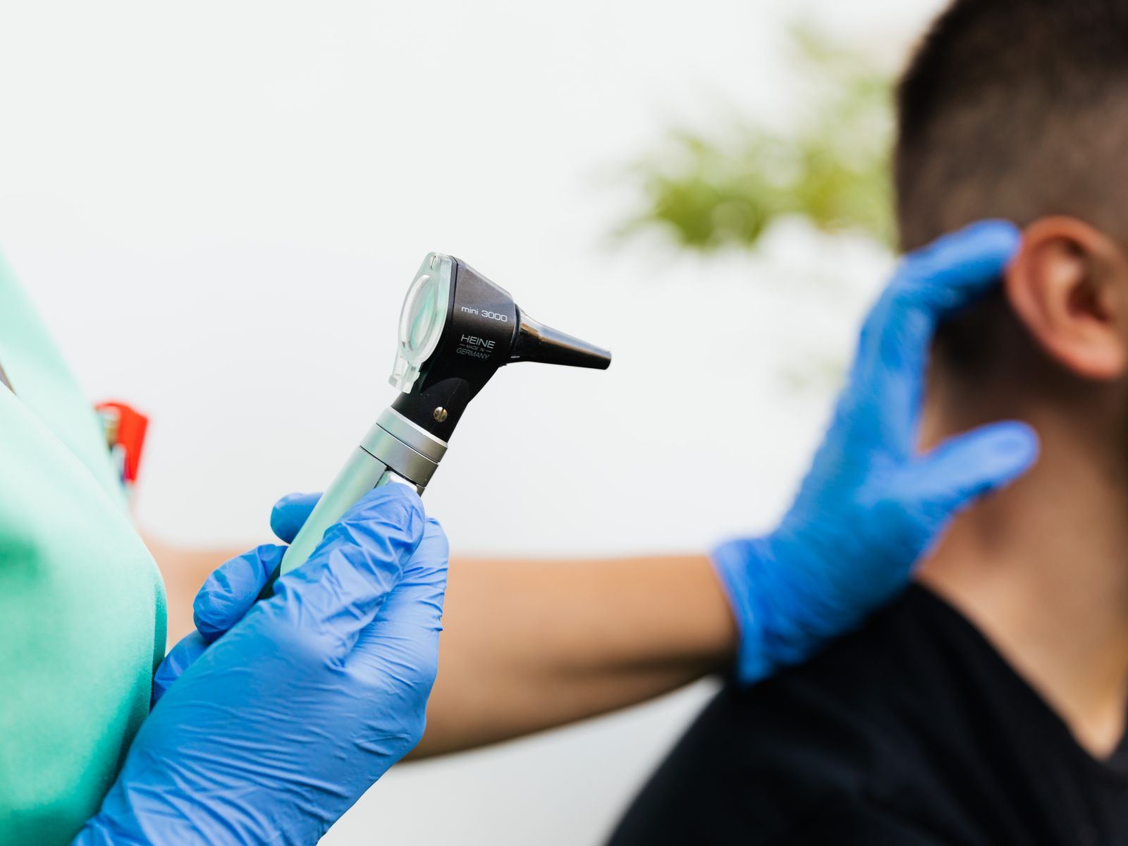 A healthcare worker examining a patient's ear with an otoscope